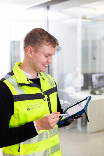 Mann schaut auf Tablet, welches er in der Hand hält